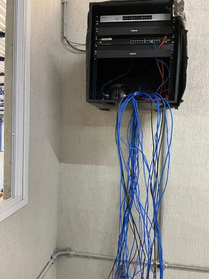 Switch Cisco SG220-26 instalado em rack de rede junto a switch Intelbras, projeto real da NC Segurança Eletrônica